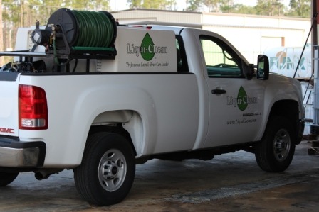 A white truck with a green hose attached to the back.