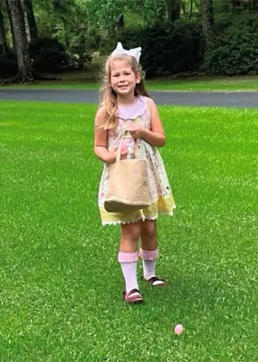 A little girl in a dress holding a purse